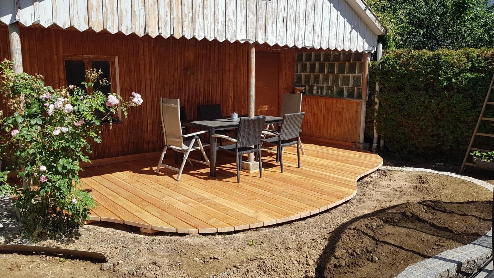 Fertige Holzterrasse mit Tisch und Stühlen vor einer Holzfassade